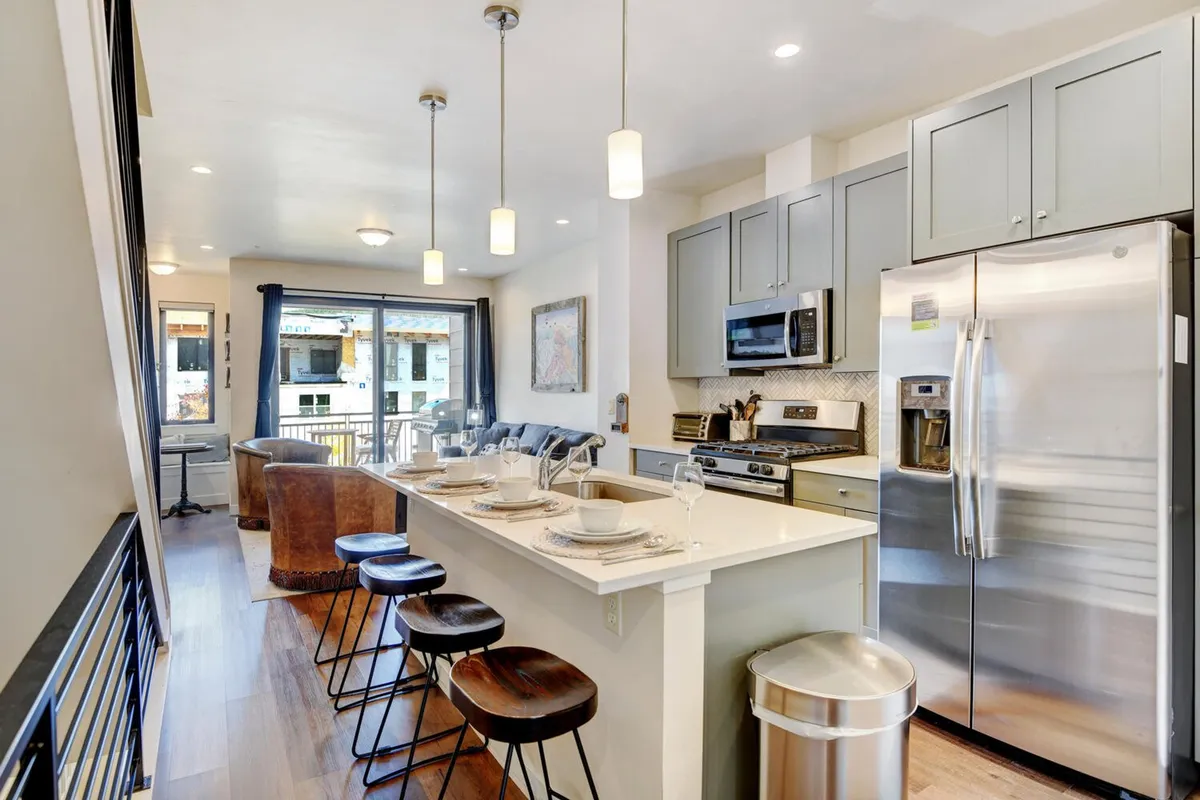 This image offers a clear perspective of the kitchen island, sleek stainless steel appliances, and a beautifully arranged dining setup. The space feels welcoming and functional, ideal for hosting family meals or entertaining guests.